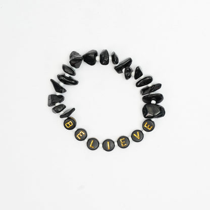 Black stone bracelet with 'BELIEVE' beads on a white background