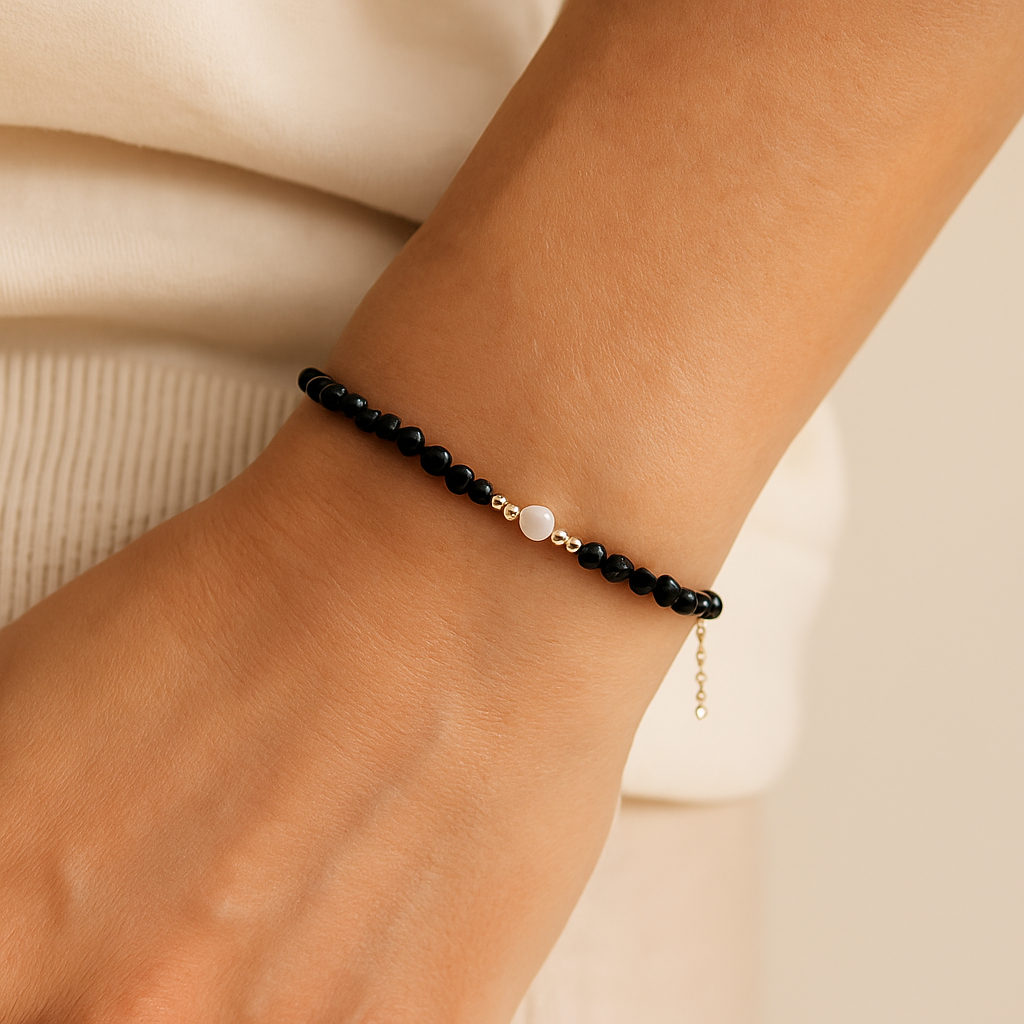 Black beaded bracelet on a wrist with a beige background    